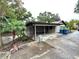 Exterior view of a carport with a car parked inside, greenery, and trash bins at 605 Wanamaker Ave, Fort Meade, FL 33841
