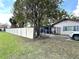 View of the property's side yard with a large tree, fence, driveway and partial view of the home at 605 Wanamaker Ave, Fort Meade, FL 33841