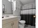 Bathroom featuring gray tile, cabinet, toilet, walk-in shower and gray shower curtain at 608 William Ave, Winter Haven, FL 33880