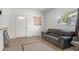 Comfortable living room featuring large window, brown couch, tile floors, and white door at 608 William Ave, Winter Haven, FL 33880