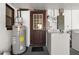 Utility room featuring water heater, water pressure tank, and access to the outside at 608 William Ave, Winter Haven, FL 33880