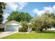 Inviting home showcasing a vibrant green lawn, lush trees, and an attached two-car garage at 612 Muskrat Dr, Kissimmee, FL 34759