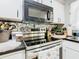 Close-up of kitchen features like a modern stainless steel oven, mosaic backsplash and black countertop at 711 Lake Dexter Cir, Winter Haven, FL 33884
