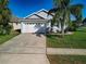 Charming single-Gathering home featuring a two-car garage, well-manicured lawn, and mature palm trees at 8001 Arrow Creek Rd, Kissimmee, FL 34747
