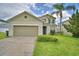 Charming two-story home with a well-maintained lawn, a two-car garage, and a palm tree at 154 Canna Dr, Davenport, FL 33897