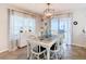 Dining room with a rustic wood table, white chairs, modern chandelier, and bright natural light at 157 Golf Aire Blvd, Haines City, FL 33844