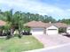 Inviting one-story home with manicured lawn, brick driveway, two-car garage, and lush landscaping at 1573 Vienna Square Dr, Winter Haven, FL 33884