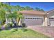 Beige single-Gathering home with a two-car garage, brick paver driveway, and tropical landscaping at 1573 Vienna Square Dr, Winter Haven, FL 33884