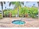 Inviting hot tub features clear blue water and a brick surround, perfect for relaxation in a tropical setting at 1573 Vienna Square Dr, Winter Haven, FL 33884