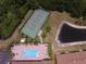Aerial view featuring a community pool, tennis court, and pond surrounded by lush landscaping and trees at 1674 Linz Ct, Winter Haven, FL 33884