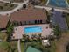 Aerial view showcases the community pool, clubhouse, and tennis courts amidst tropical landscaping at 1674 Linz Ct, Winter Haven, FL 33884