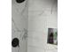 Close-up of the luxurious marble tiled shower featuring sleek fixtures and built-in shelving at 1681 Waterview Loop, Haines City, FL 33844