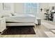 Sunlit bedroom with a comfortable bed, ottoman, and wood floors at 1760 Carnostie Rd, Winter Haven, FL 33884