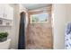 Bathroom featuring a step-in shower with neutral colored tiles, a window, and a grey shower curtain at 177 Costa Loop, Auburndale, FL 33823