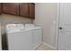 Bright laundry room features a white washer and dryer with overhead cabinets at 225 Summershore Dr, Auburndale, FL 33823