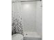 Bathroom with a white tile shower with dark leaf-patterned shower curtain, white walls, and tiled flooring at 230 Cove At Eagle Lake Cir, Eagle Lake, FL 33839
