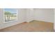 Bright bedroom with tan carpet, and a window view of lush trees at 230 Cove At Eagle Lake Cir, Eagle Lake, FL 33839