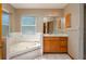 Spa-like bathroom with a soaking tub, wood vanity, and marble tile, creating a luxurious retreat at 2390 Lake Easy Rd, Babson Park, FL 33827