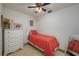 A cozy bedroom features a single bed with bright red quilt, white dresser, and neutral wall color at 2390 Lake Easy Rd, Babson Park, FL 33827