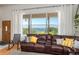 The bright living room showcases water views from a large window and a comfortable leather couch at 2390 Lake Easy Rd, Babson Park, FL 33827