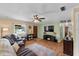 Cozy living room with a ceiling fan, leather sofa, wood-look flooring, and a view through the window at 275 Cherry Laurel Ln, Winter Haven, FL 33880