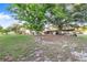 Spacious backyard featuring mature trees, a covered parking area, and a glimpse of the home's exterior at 302 W Gates Ave, Lake Hamilton, FL 33851