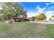 Exterior showcasing covered parking, a two-car garage, and a spacious green lawn in a serene setting at 302 W Gates Ave, Lake Hamilton, FL 33851