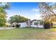 Exterior view of the home featuring a stone chimney, well-maintained lawn, and a convenient carport at 302 W Gates Ave, Lake Hamilton, FL 33851