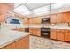 Traditional kitchen boasts wood cabinets, black appliances, tiled backsplash, and unique ceiling lighting at 302 W Gates Ave, Lake Hamilton, FL 33851