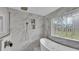 Luxurious bathroom featuring marble tiled walls, a stylish glass shower and soaking tub at 317 Oak Trl, Lakeland, FL 33813