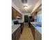 Galley kitchen featuring wood cabinetry, white countertops, and modern appliances at 32 Cedar Dr, Davenport, FL 33837