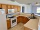 Bright kitchen featuring white appliances, tile flooring, and wooden cabinetry at 351 Columbo St, Winter Haven, FL 33880