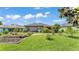 Expansive backyard featuring lush green grass, mature trees, a garden, and a covered patio at 364 Lake Vista Dr, Auburndale, FL 33823