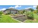 A large backyard featuring green grass, a garden, and a patio area with a grill at 364 Lake Vista Dr, Auburndale, FL 33823