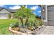 Beautiful landscaping featuring a stone border with flowering plants, small palms, and decorative statuary at 364 Lake Vista Dr, Auburndale, FL 33823