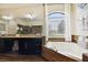 Bright bathroom showcasing a soaking tub, wooden accents, granite counters, and natural light at 3833 Bowfin Trl, Kissimmee, FL 34746