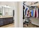 Bathroom featuring a dark wood vanity with granite countertops and a separate walk-in closet with organized storage at 3833 Bowfin Trl, Kissimmee, FL 34746
