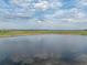 Expansive view of pond reflecting cloudy sky creates a serene scene in this waterfront real estate setting at 4081 Dunmore Dr, Lake Wales, FL 33859