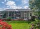 Backyard view with screened pool, manicured lawn, and colorful landscaping creates a relaxing and inviting outdoor space at 428 Terranova St, Winter Haven, FL 33884