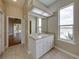 Bright bathroom features a large mirror, white vanity, and natural light from a nearby window at 428 Terranova St, Winter Haven, FL 33884