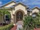 Home's arched entrance features elegant columns and a beautifully landscaped front yard with vibrant plants and lush greenery at 428 Terranova St, Winter Haven, FL 33884