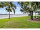 Expansive grassy lawn leads to serene lakefront with trees; showcasing the outdoor space at 4365 Canal Rd, Lake Wales, FL 33898