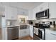 Well-lit kitchen featuring stainless steel appliances, white cabinets, a farmhouse sink, and modern fixtures at 4940 Foxdale Dr, Lakeland, FL 33810