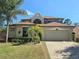 Charming home showcasing manicured landscaping, mature palms, and a spacious two-car garage at 4962 Sweet Cedar Cir, Orlando, FL 32829