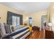 Sunlit bedroom featuring hardwood floors, yellow walls, and blue patterned curtains at 501 Main St, Lake Hamilton, FL 33851