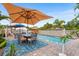 Inviting pool area with brick pavers, lounge chairs, dining table and umbrellas at 501 Main St, Lake Hamilton, FL 33851