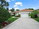 Inviting single-story house featuring a tile roof, white stucco, a two-car garage, and well-maintained landscaping at 530 Greenway Dr, Lake Wales, FL 33898