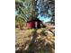 Exterior view of the backyard shed featuring red siding and a white door with a ladder leaning to the left at 620 Se Oleander Se Dr, Winter Haven, FL 33880