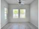 A bright bedroom featuring light gray wood floors, white walls, and two windows at 625 Disa Dr, Davenport, FL 33837