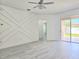 Bright living room featuring gray wood floors, decorative wall, stylish ceiling fan, and sliding glass doors at 625 Disa Dr, Davenport, FL 33837